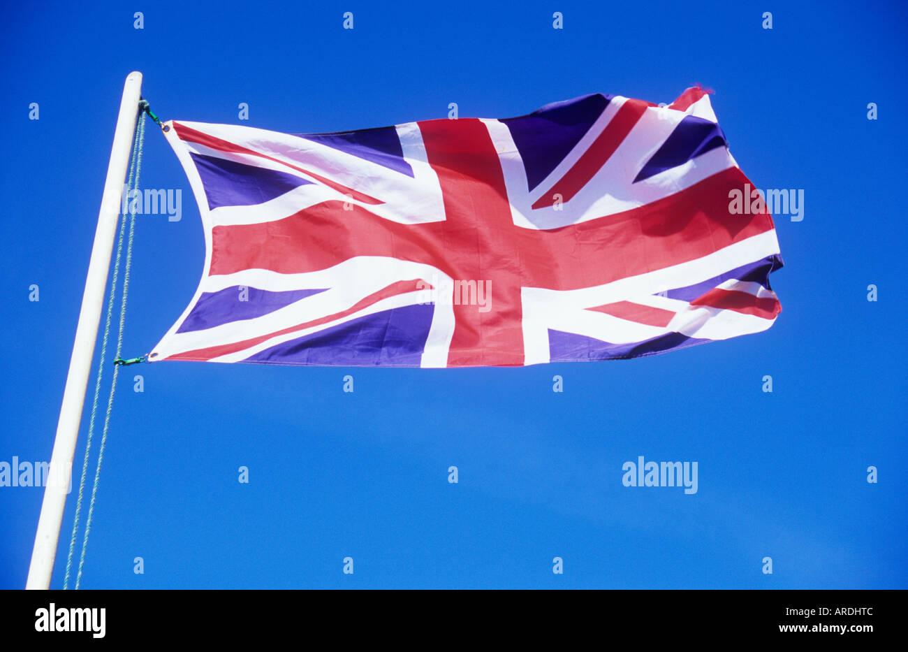Union Jack flag fluttering from flagpole against clear blue sky Stock Photo