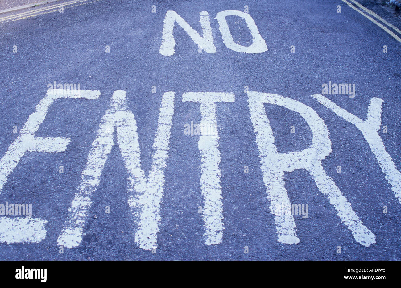 Wide angle view of the words No Entry painted in large letters on tarmac road surface with yellow lines also visible Stock Photo