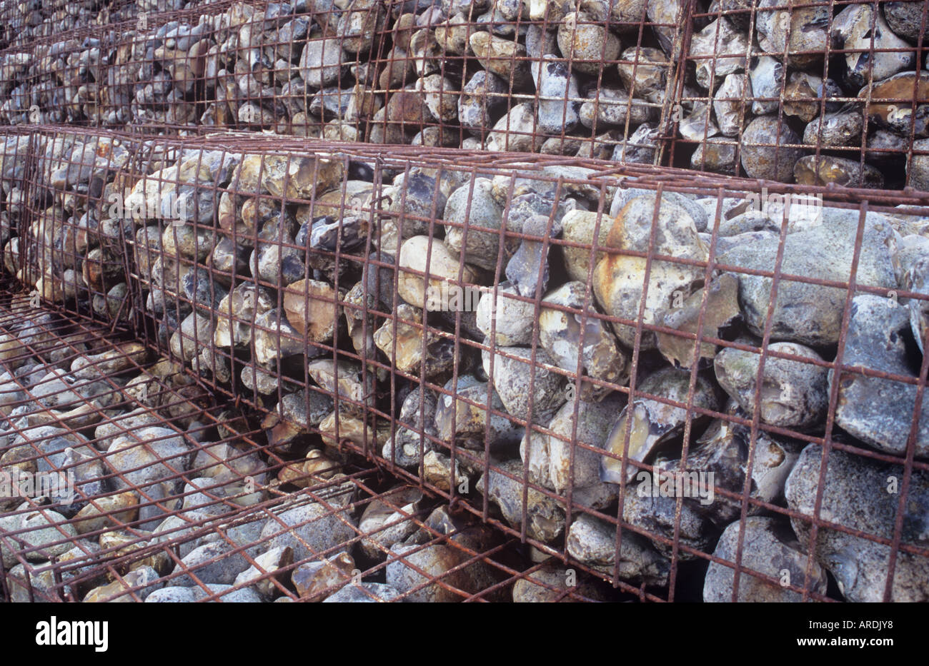 Detail of wire cages or gabions containing large stones stacked and stepped as defence against coastal erosion Stock Photo