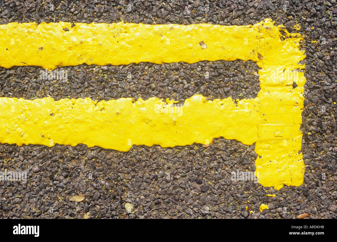 Detail from directly above of newly painted double yellow lines with end bar on a black tarmac road surface Stock Photo