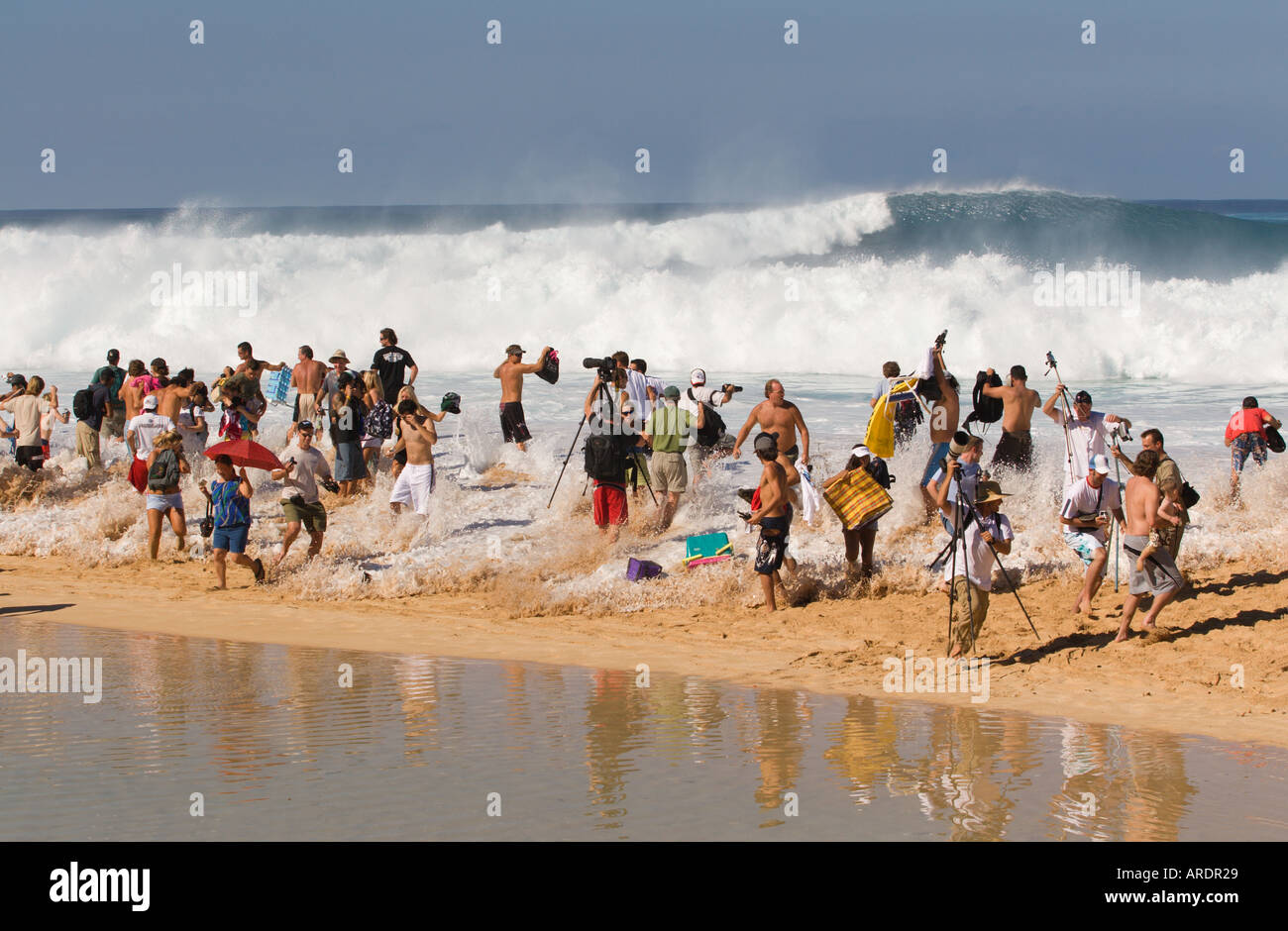 Photographers some with tripods in danger as they get caught out by an ocean surge on the North Shore of Oahu Island Hawaii Stock Photo