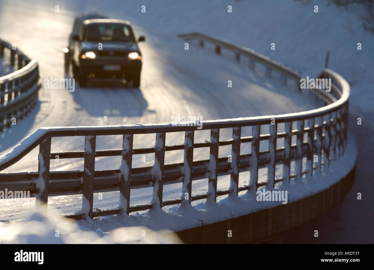Metallic snowy road bridge railing and car driving on the road at Winter , Finland Stock Photo