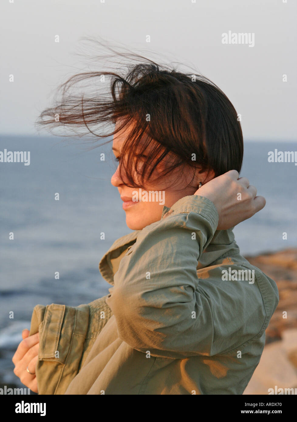 head and shoulders portrait of young woman Windy Summer Sunset Rockport Halibut Point State Park Massachusetts Stock Photo