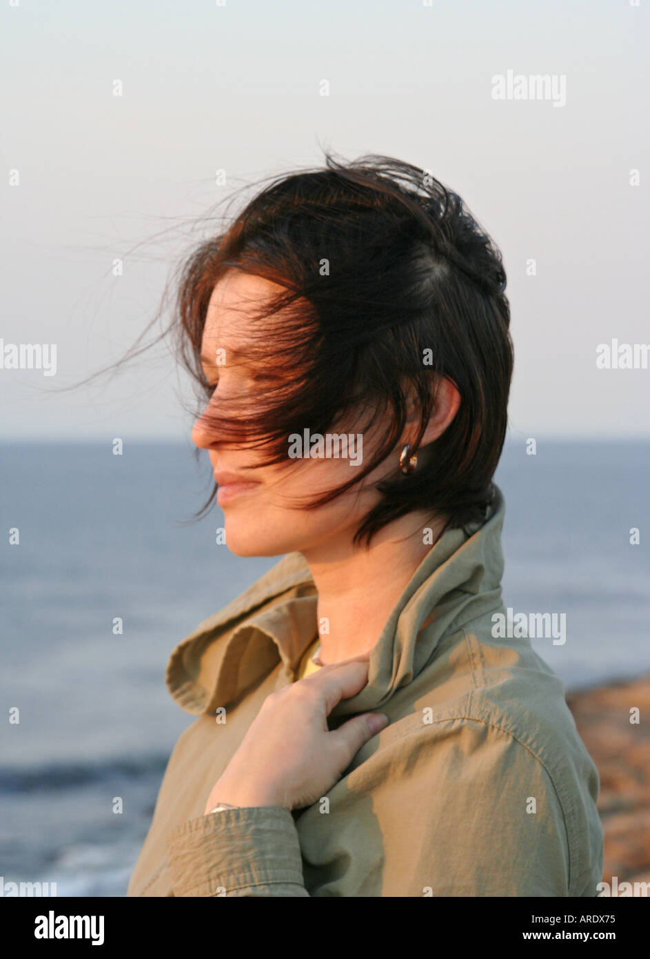 head and shoulders portrait of young woman Windy Summer Sunset Rockport Halibut Point State Park Massachusetts Stock Photo