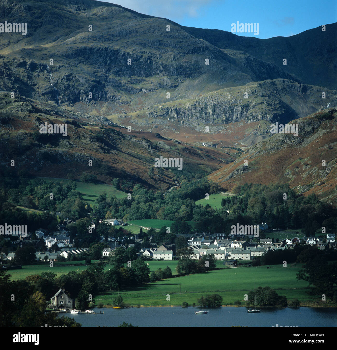 View over Ullswater to lakeside village autumn coloured fells behind Cumbria Stock Photo