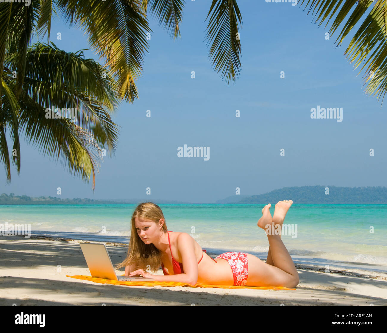 A woman on a beach with a laptop computer Stock Photo