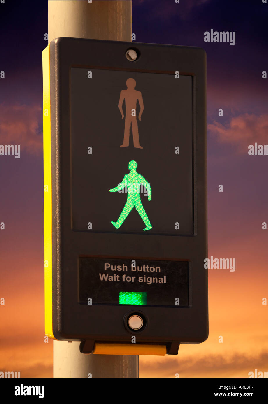 PEDESTRIAN CROSSING CONTROL BOX WITH ILLUMINATED ICON OF WALKING GREEN MAN AT TWILIIGHT Stock Photo