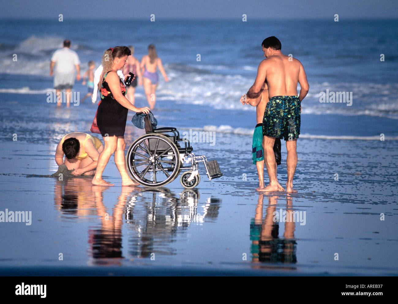 Family on beach with child's wheelchair in Myrtle Beach South Carolina USA having fun in a warm