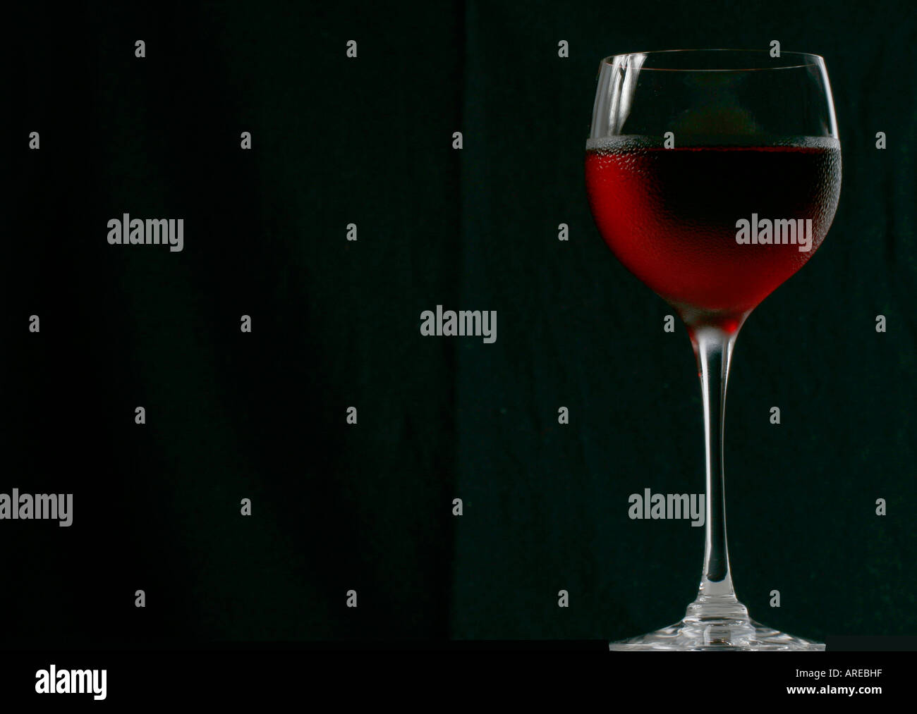 Profile view of a glass of chilled rose blush wine against a black