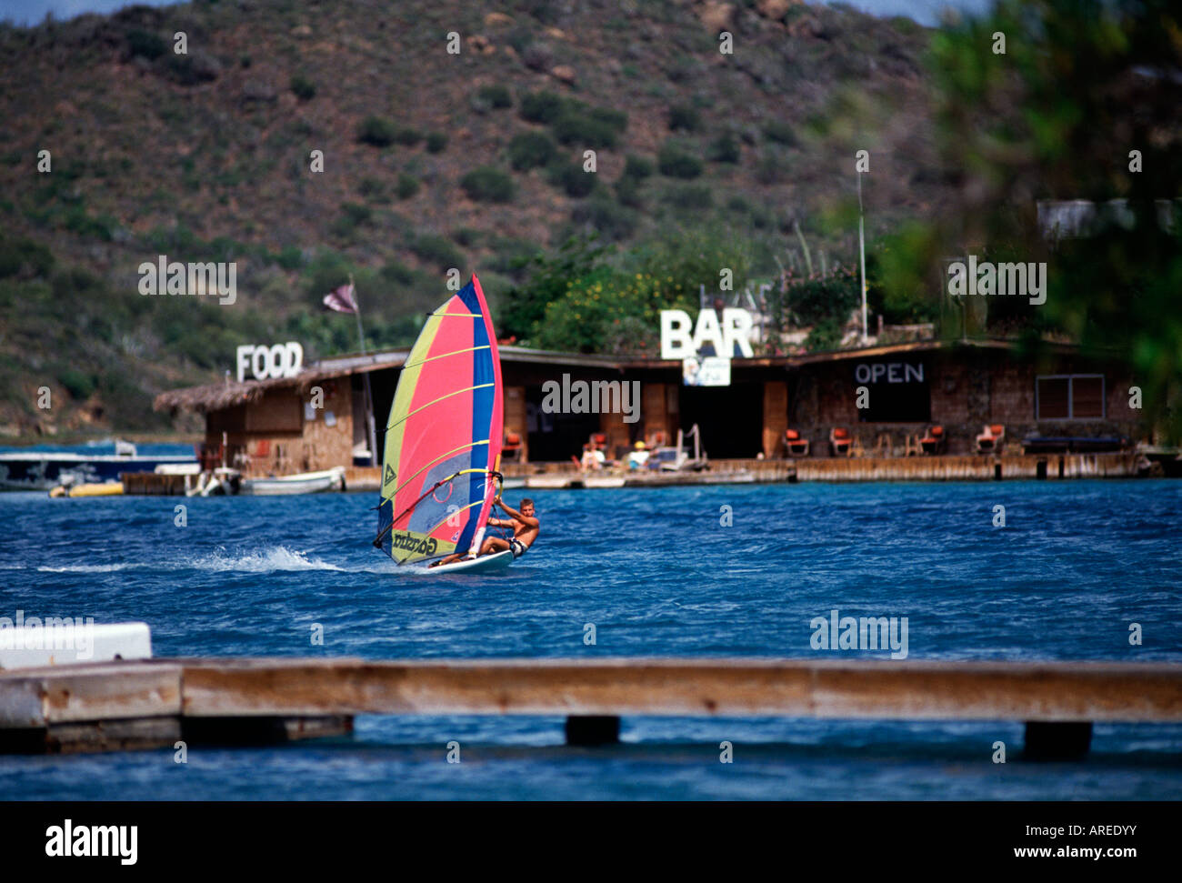 BVI Virgin Gorda North Sound windsurfer Pirate s Pub in background Stock Photo
