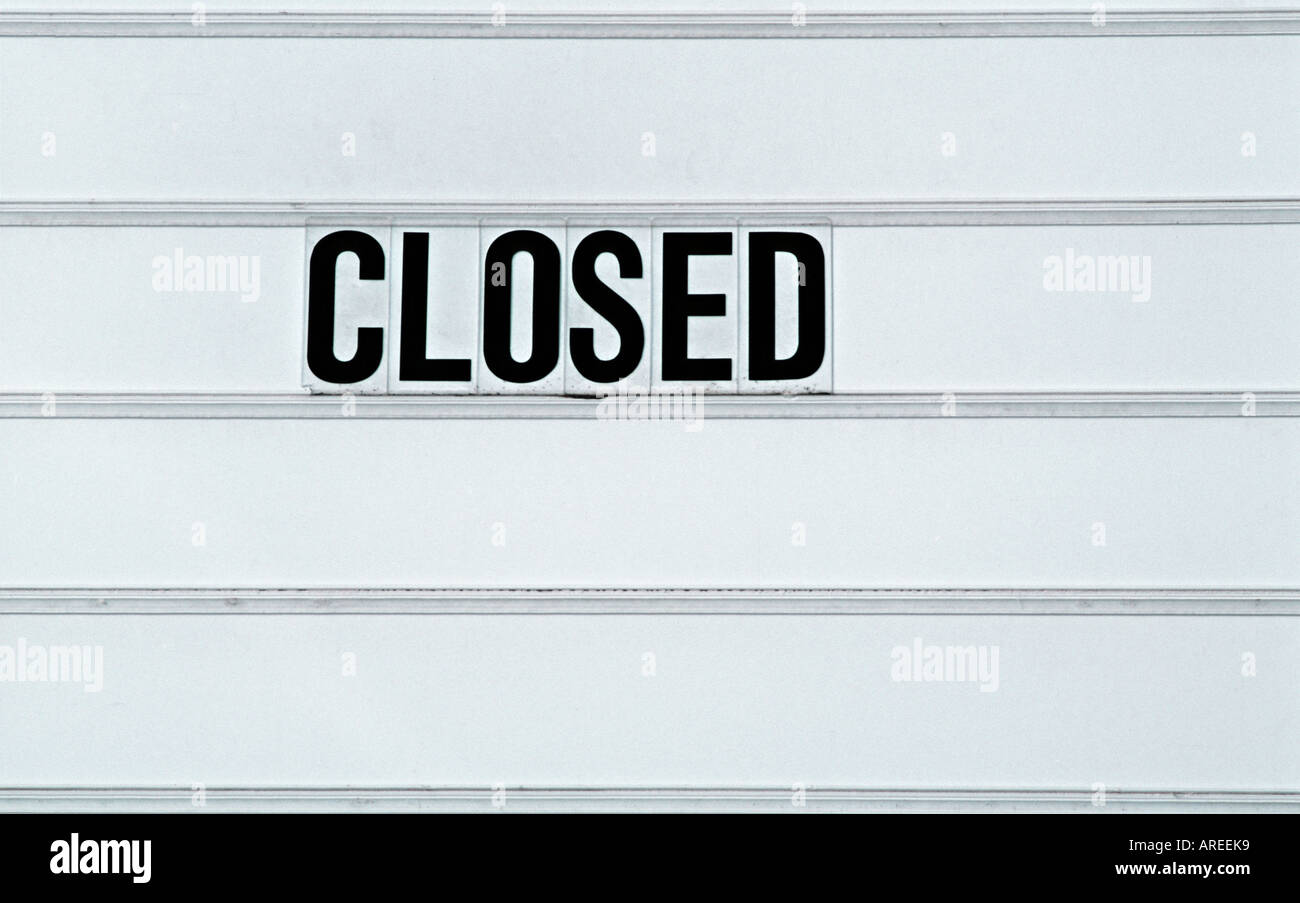 The word CLOSED in bold black letters on a white backlit sign Stock
