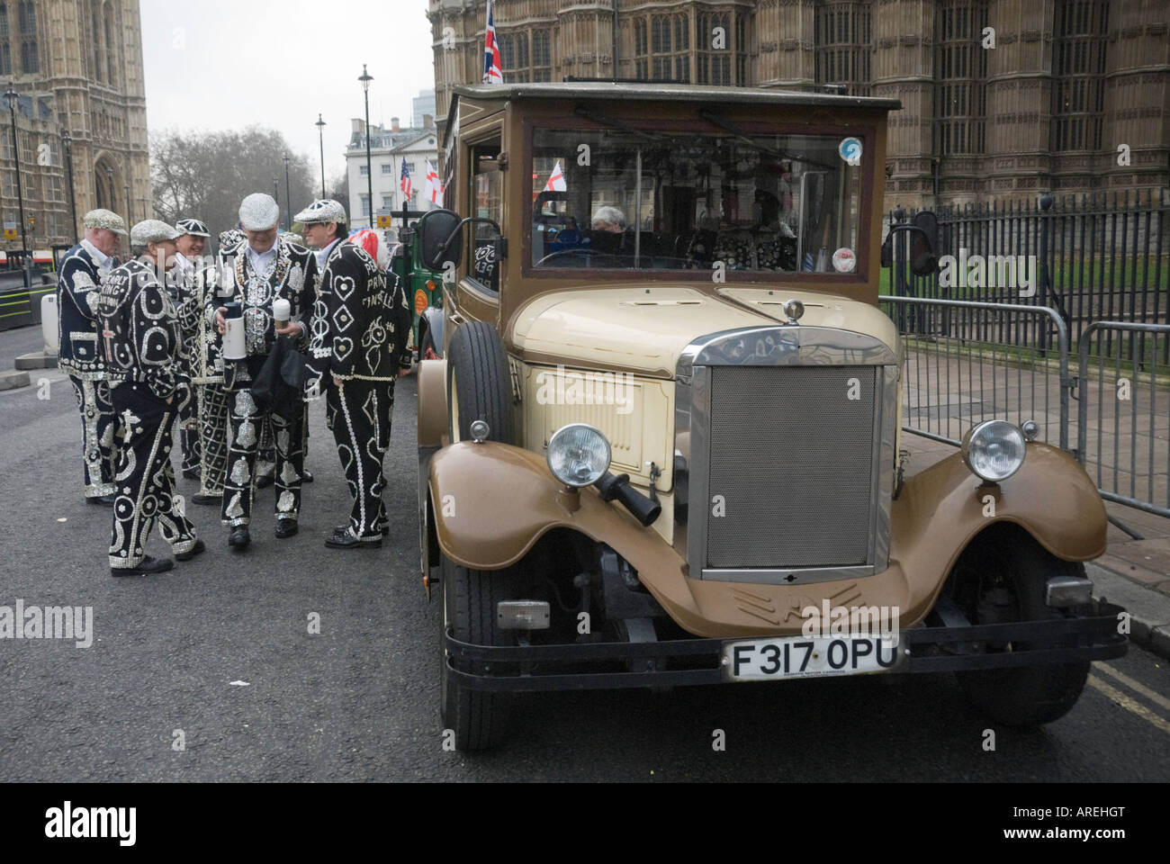 A vintage charabanc parked in front of Westminster Abbey and the Houses of Parliament with a group of Pearly Kings, London. Stock Photo