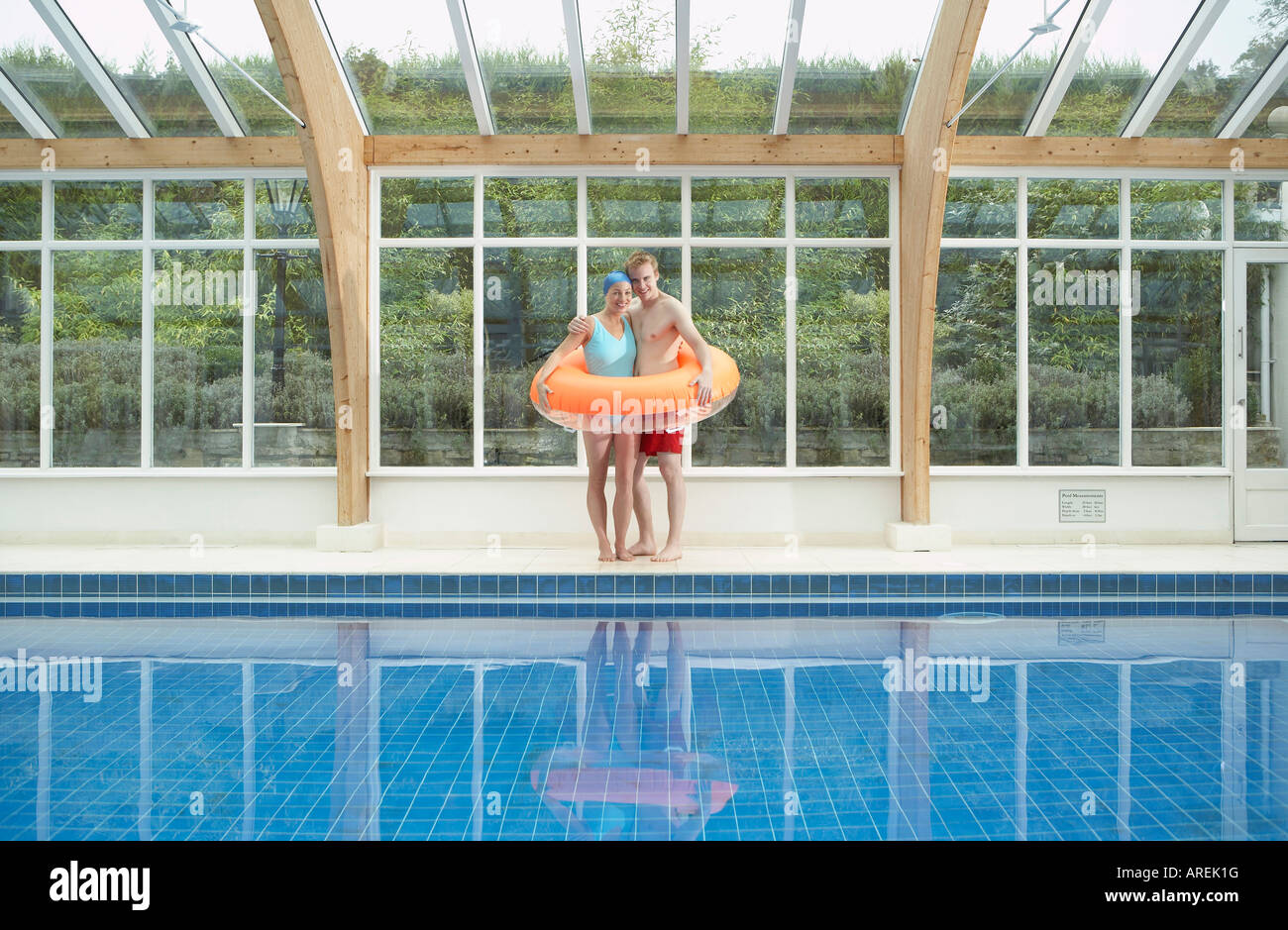 Couple standing in rubber ring by pool Stock Photo