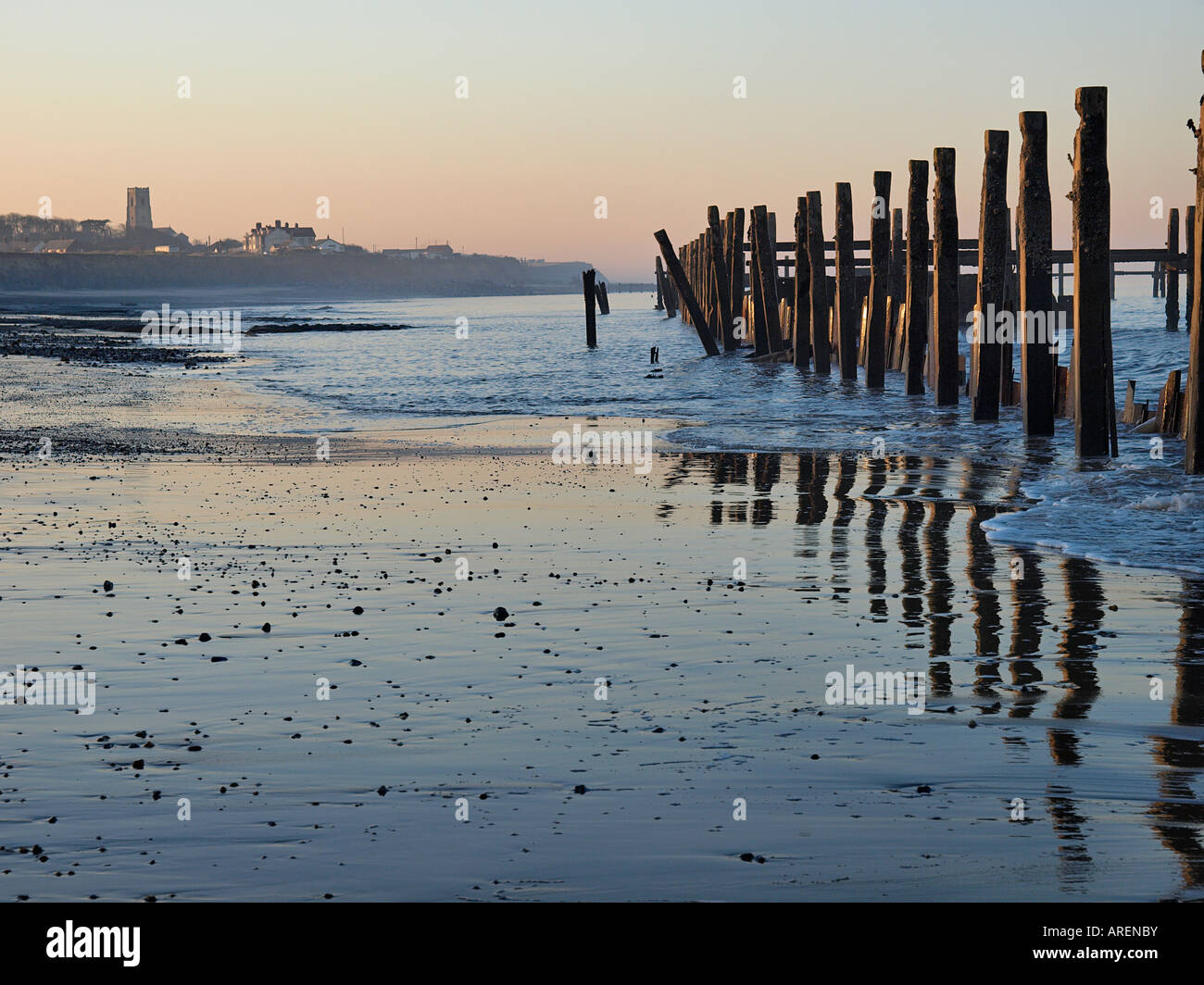 LOW TIDE ON HAPPISBURGH BEACH WITH BROKEN SEA DEFENCES REFLECTED IN WET ...