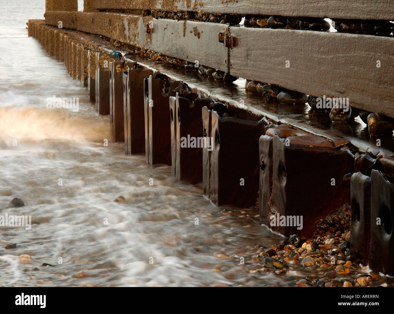 WOOD AND STEEL GROYNE ON HAPPISBURGH BEACH WITH SEA WATER AND WAVES ON SHINGLE, NORFOLK ENGLAND UK Stock Photo