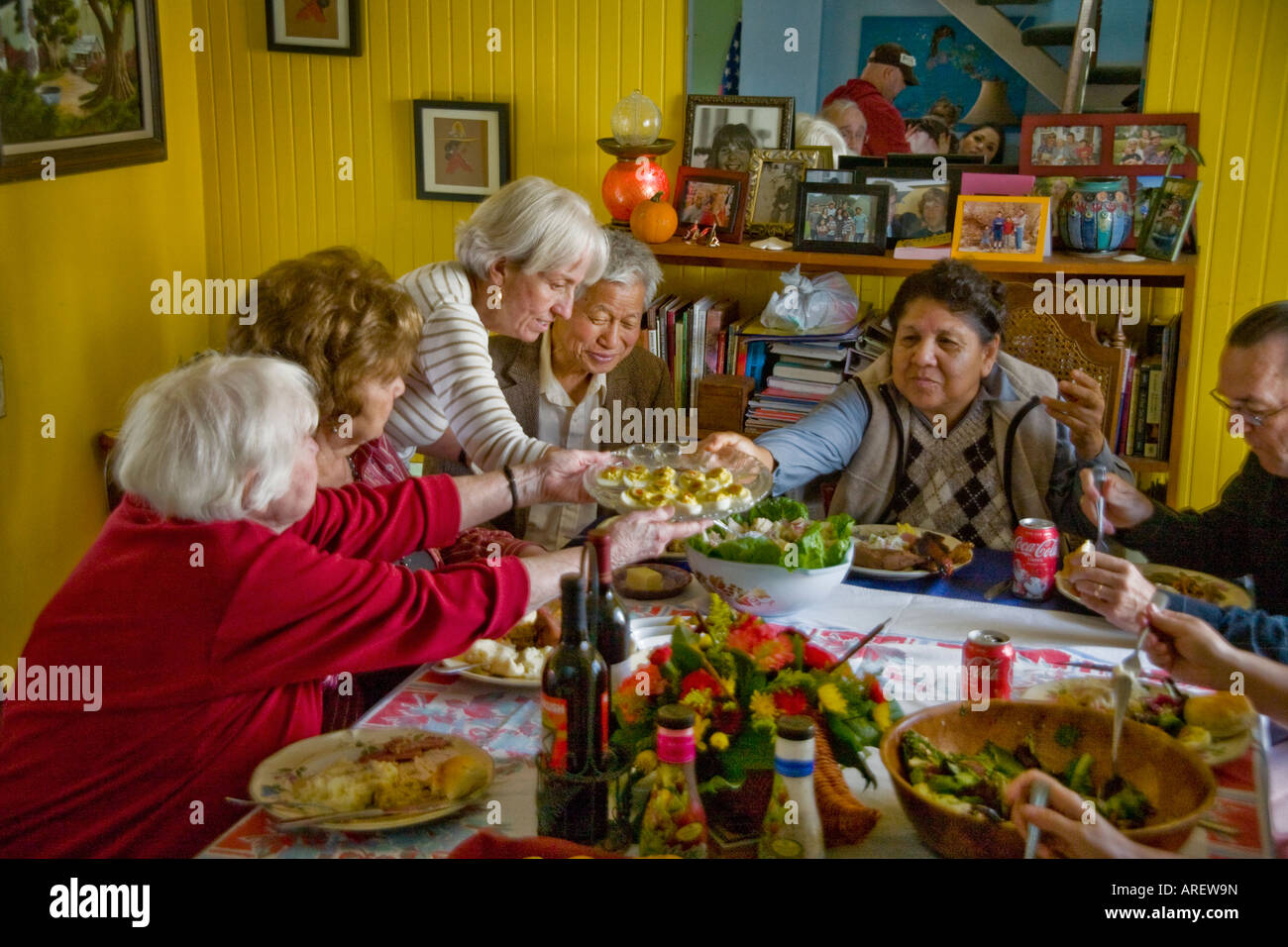 Family members and guests of many ethnicities eat Thanksgiving dinner
