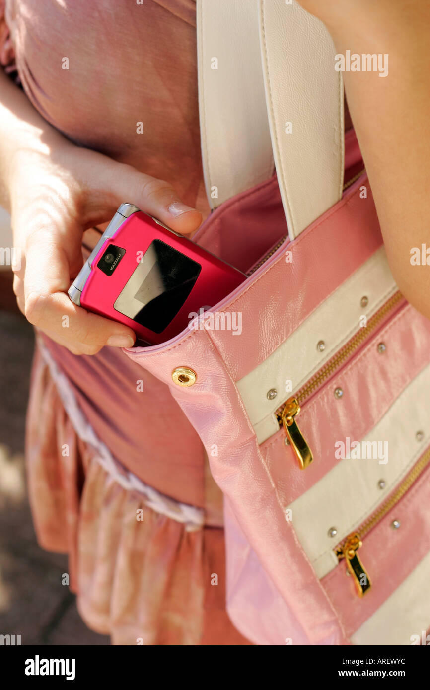 Girl placing mobile phone into bag Stock Photo