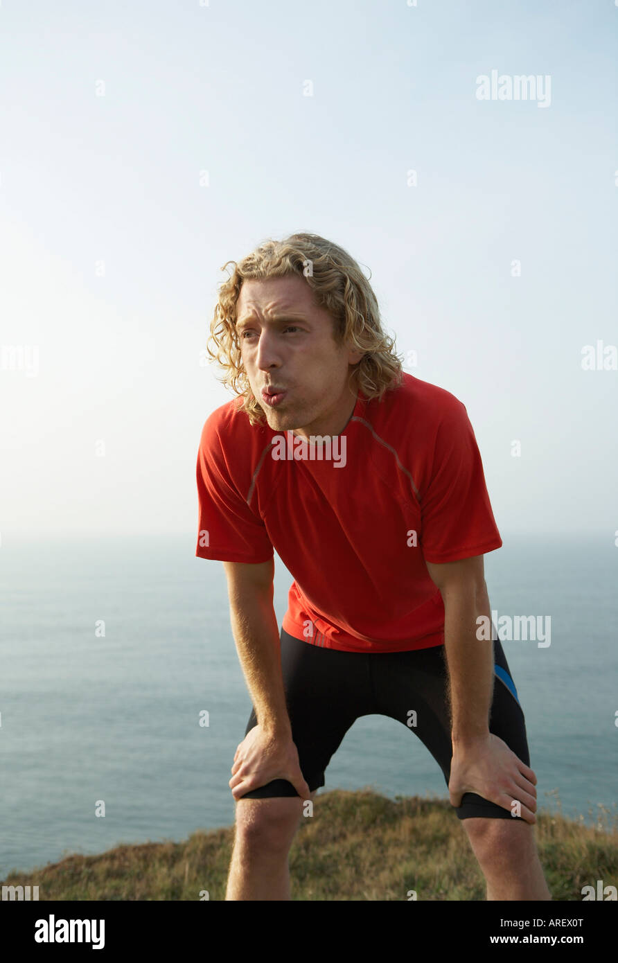 A young Male runner catches his breath Stock Photo