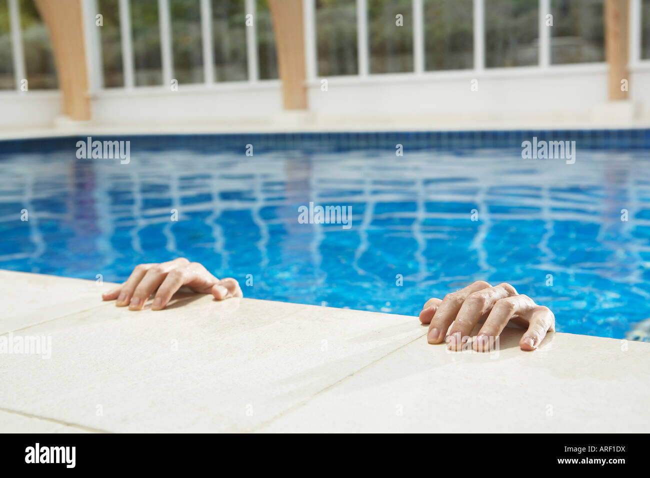 Two hands on the side of a pool Stock Photo