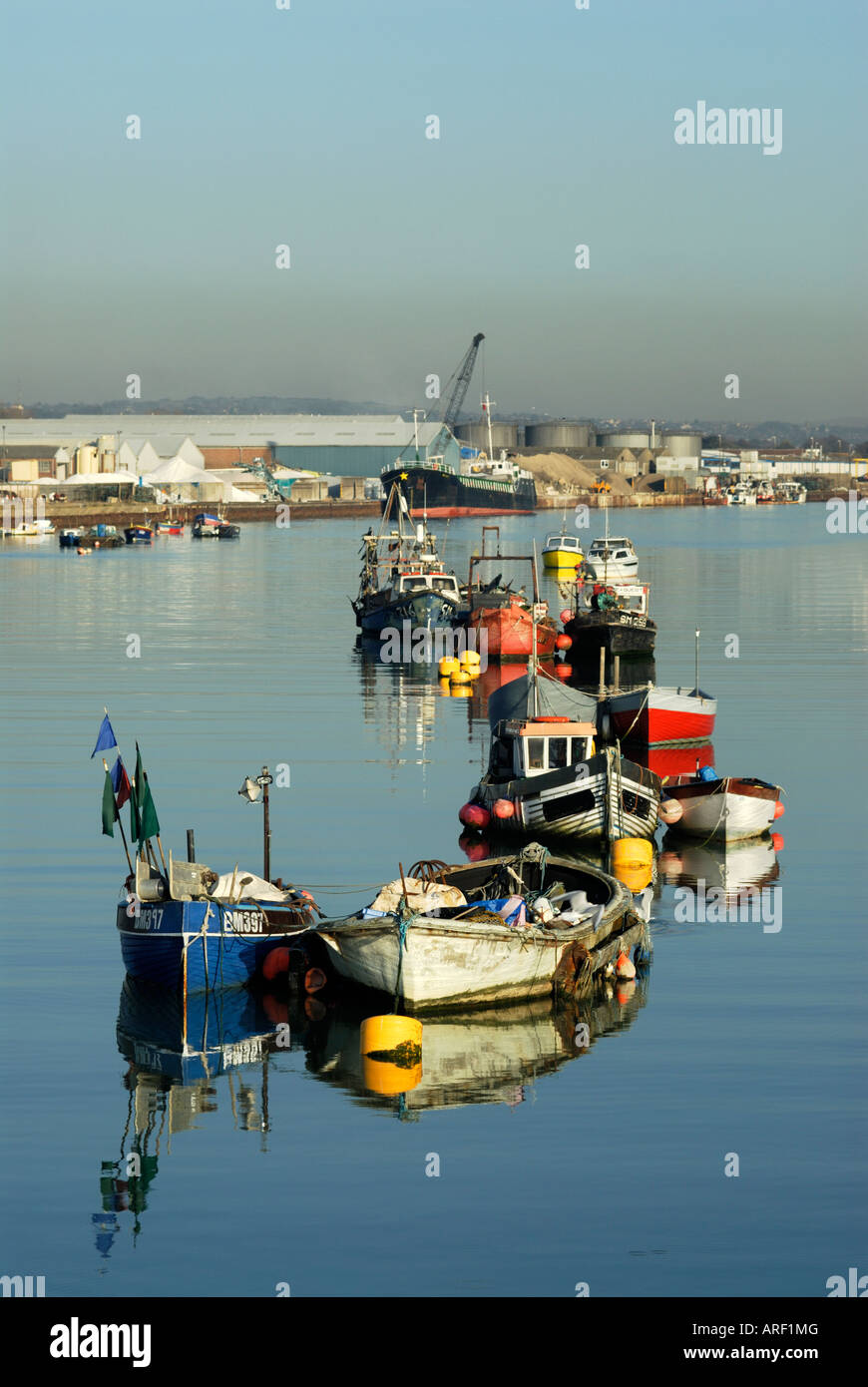 Fishing boats moored at Shoreham on the river Adur. Part of Shoreham port and cargo freighter in background Stock Photo