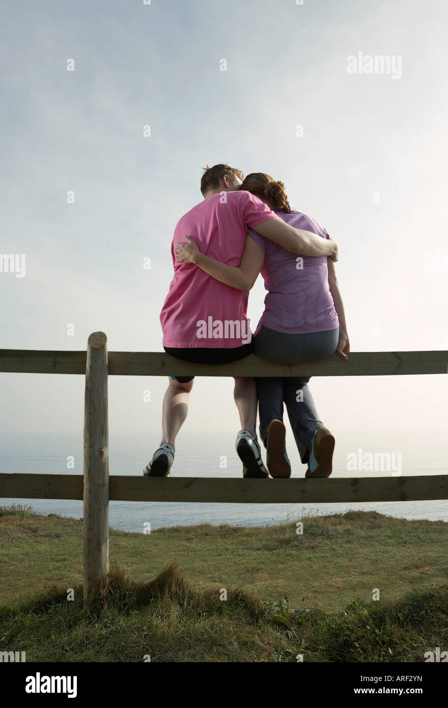 A Couple hug sitting on a country fence Stock Photo
