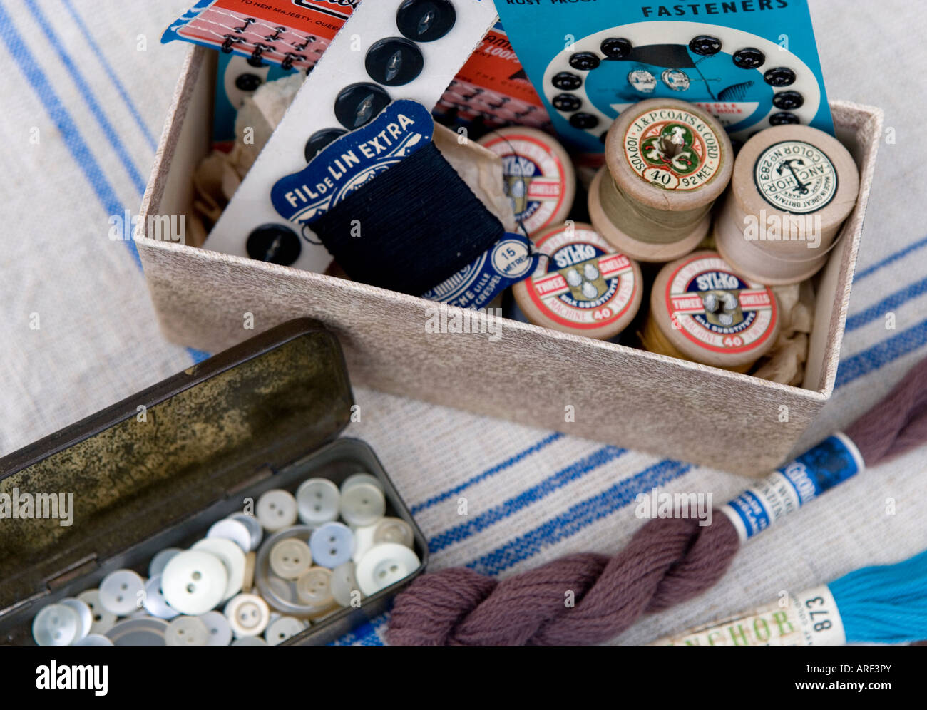 Used and recycled buttons in a vintage tin with a box of cotton reels, pressstuds and hooks and eyes Stock Photo