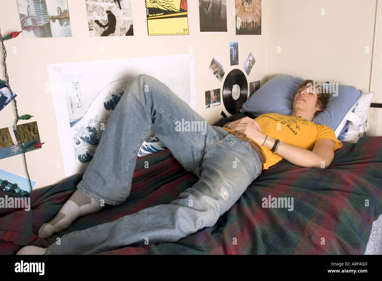 Young man laying in his bed ready to take a nap in his room Stock Photo