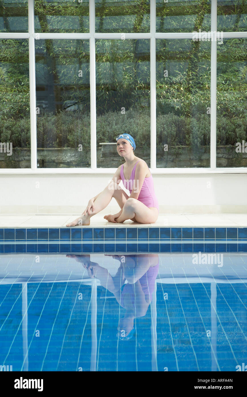 Woman sitting by swimming pool Stock Photo