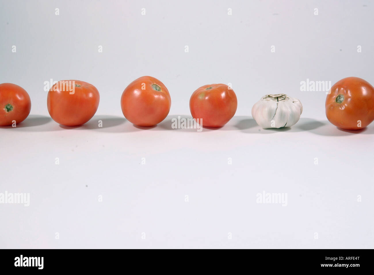 A clove of garlic amid red tomatoes Stock Photo - Alamy