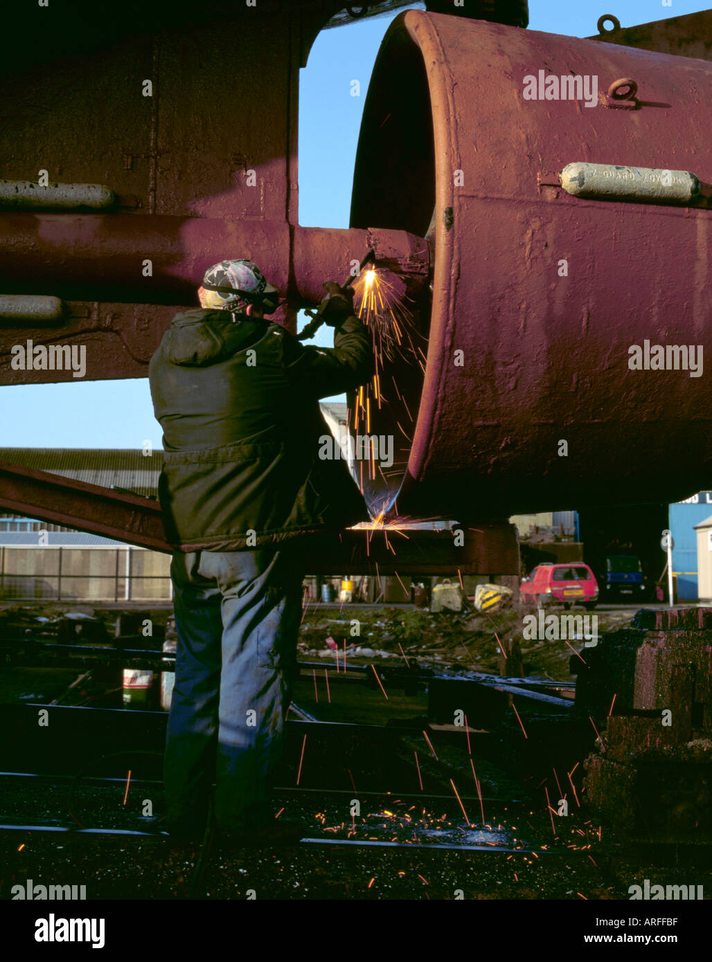 Man using an oxyacetylene burner on a ship's propellor shaft, in a ship repair yard. Stock Photo