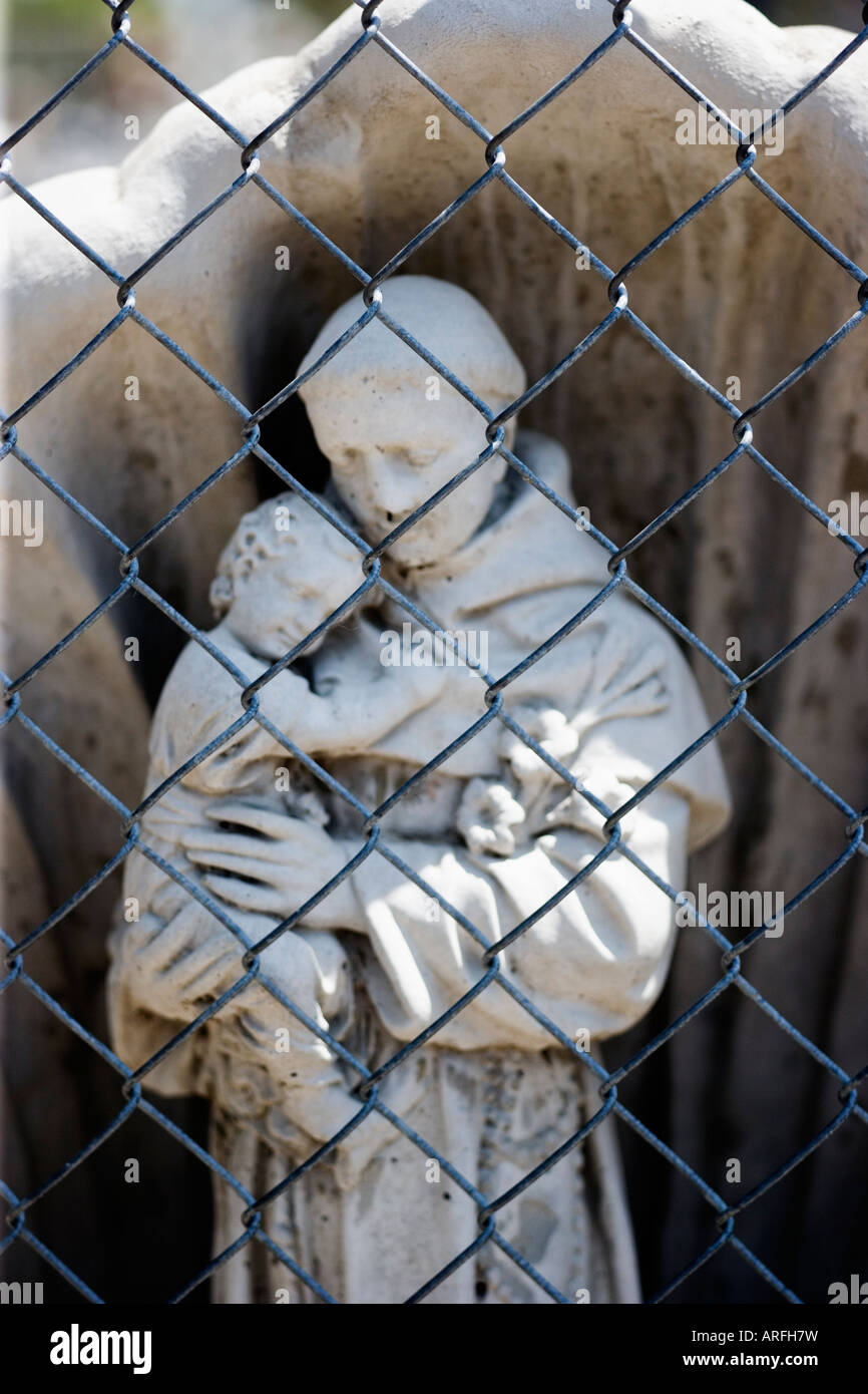 Religious garden statue behind chain link fence Stock Photo - Alamy