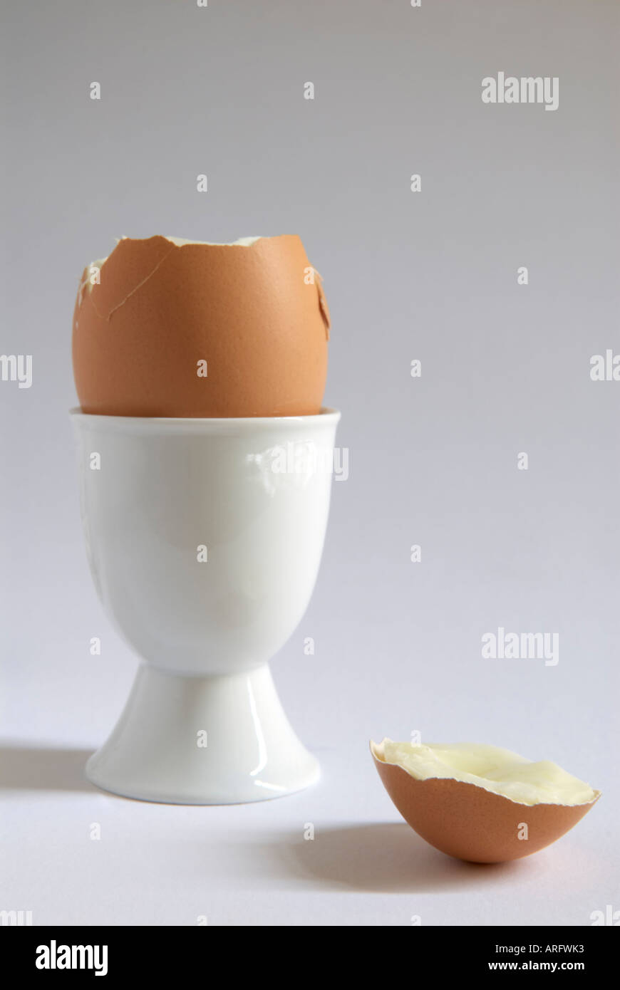 A boiled egg  with" top removed"  in an "white egg cup" Stock Photo