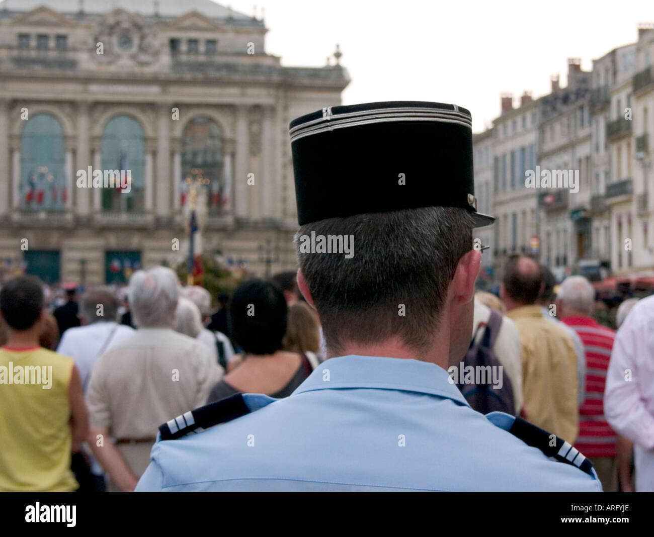 the back of a french policeman's head with montpellier's main square and opera house in the background Stock Photo