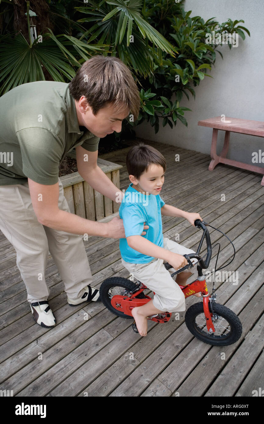 Boy riding a bike with father Stock Photo Alamy