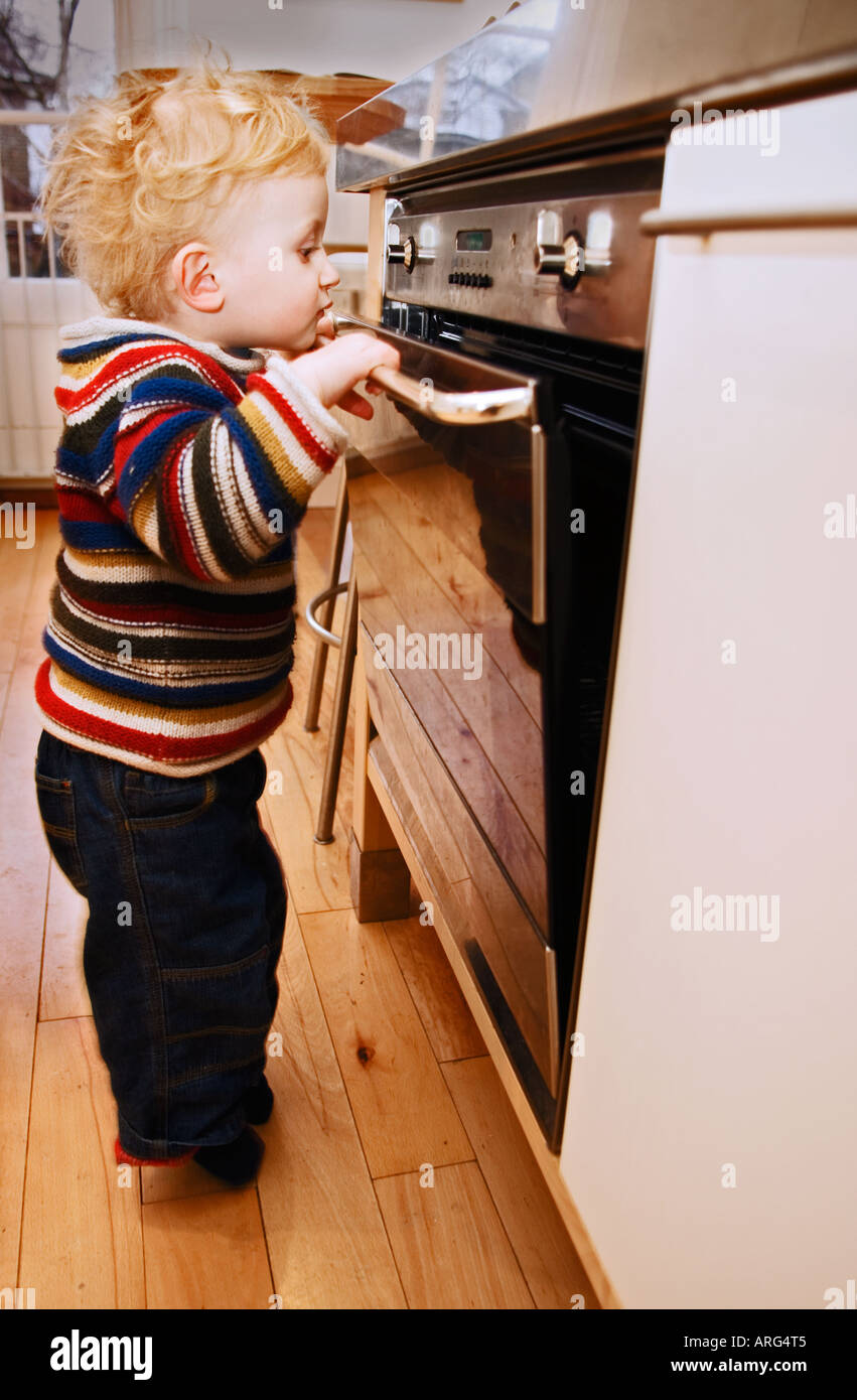 Toddler boy opening oven door Stock Photo Alamy
