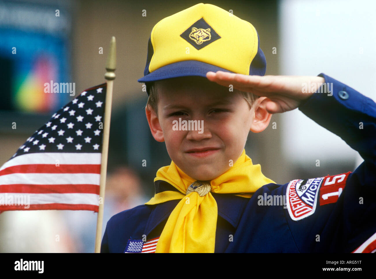 American Cub Scout salutes as he holds an American flag Stock Photo