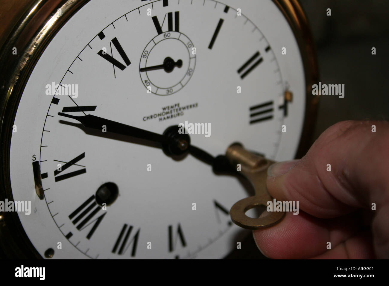 brass ships clock being wound up Stock Photo - Alamy
