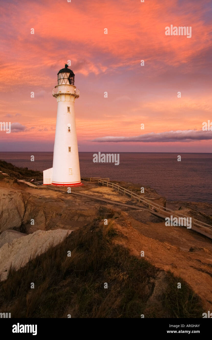 Castlepoint Lighthouse on the Wairarapa coast at sunset. Setting sun lights up the clouds Stock Photo