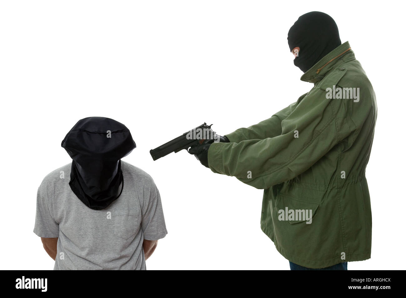 Armed man holding a gun to the head of a hooded man Stock Photo