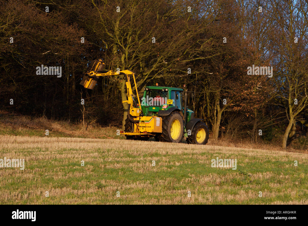 Hedge Cutting using a John Deere Tractor with rear mounted flail cutter UK Stock Photo