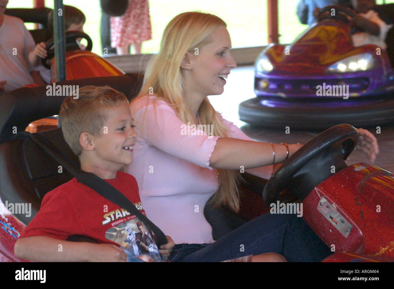 Mother and son playing on bumper cars in a funfair Stock Photo
