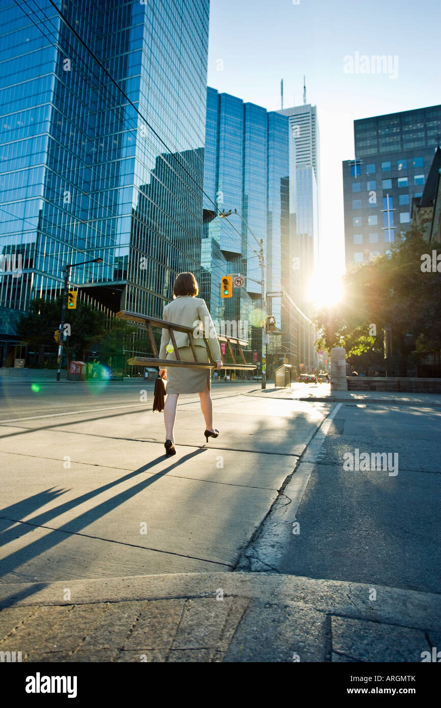 Businesswoman Crossing Street and Carrying Ladder Stock Photo