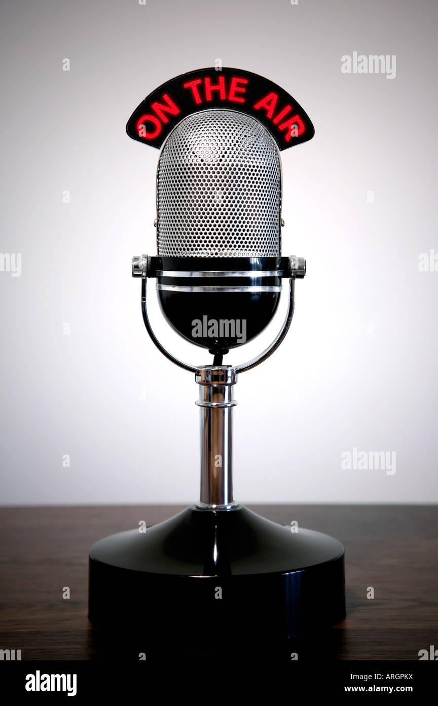 Retro microphone with an On the Air illuminated sign on a desk vignetted background Stock Photo