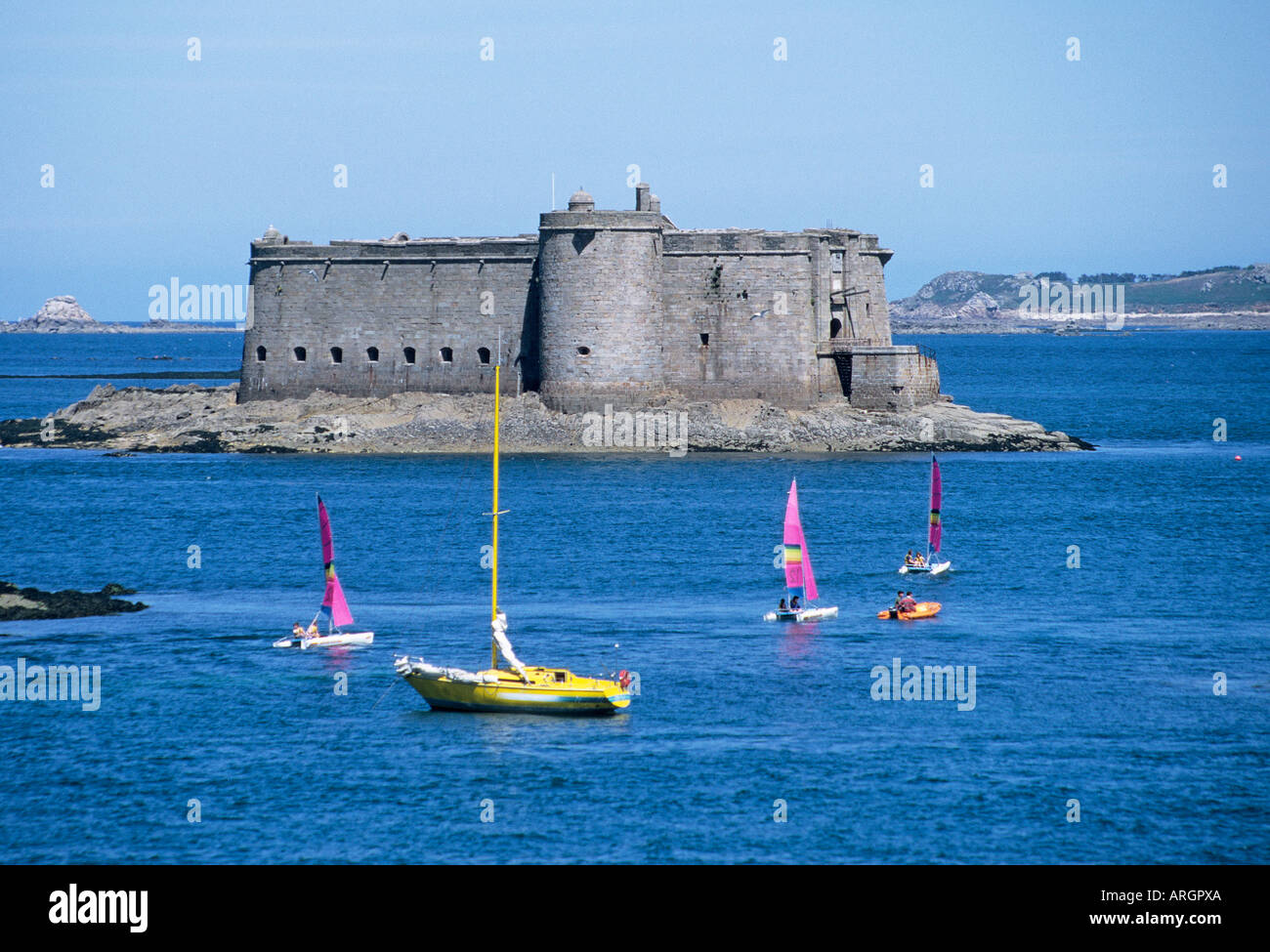 Dinghy sailors enjoy a sail with the added benefit of a close up view of the chateau du Taureau which was built as a fortress in 1552 Stock Photo
