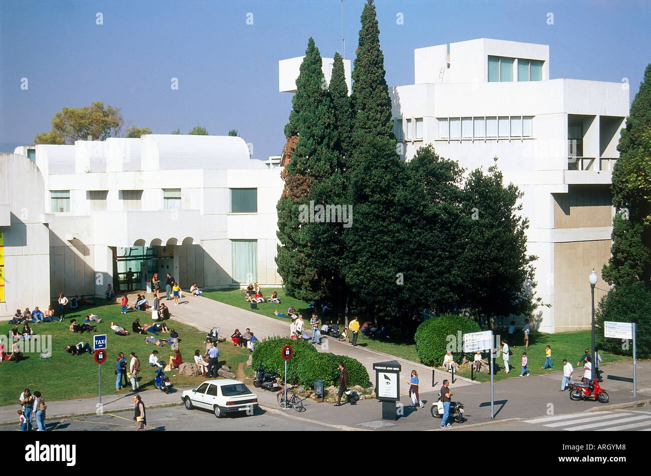 Visitors relax on the lawns in front of the white building of the Fundacio Joan Miro which was designed by Miro s friend in 1975 as a forum for experimentation and study The Fundacio contains a permanent collection and holds special exhibitions Barcelona Stock Photo