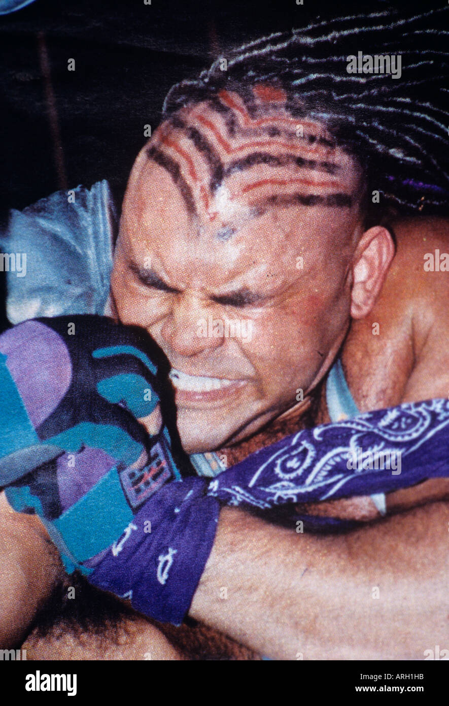 A photograph from a popular Mexican sports magazine of a grisly wrestler with face screwed up as he squashes his opponent in his arms Stock Photo