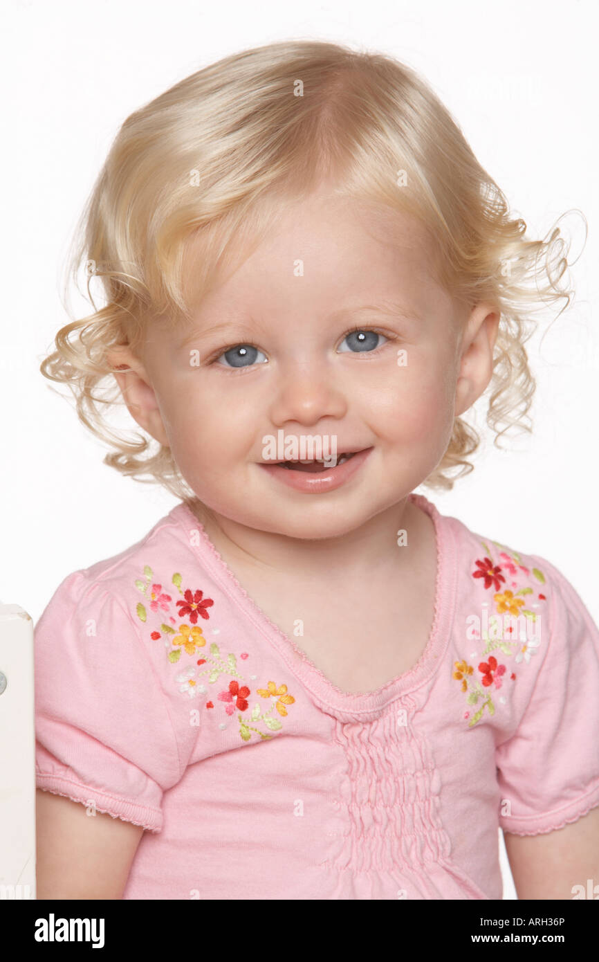 A blonde baby girl in a pink t-shirt smiles against a white background  Stock Photo - Alamy