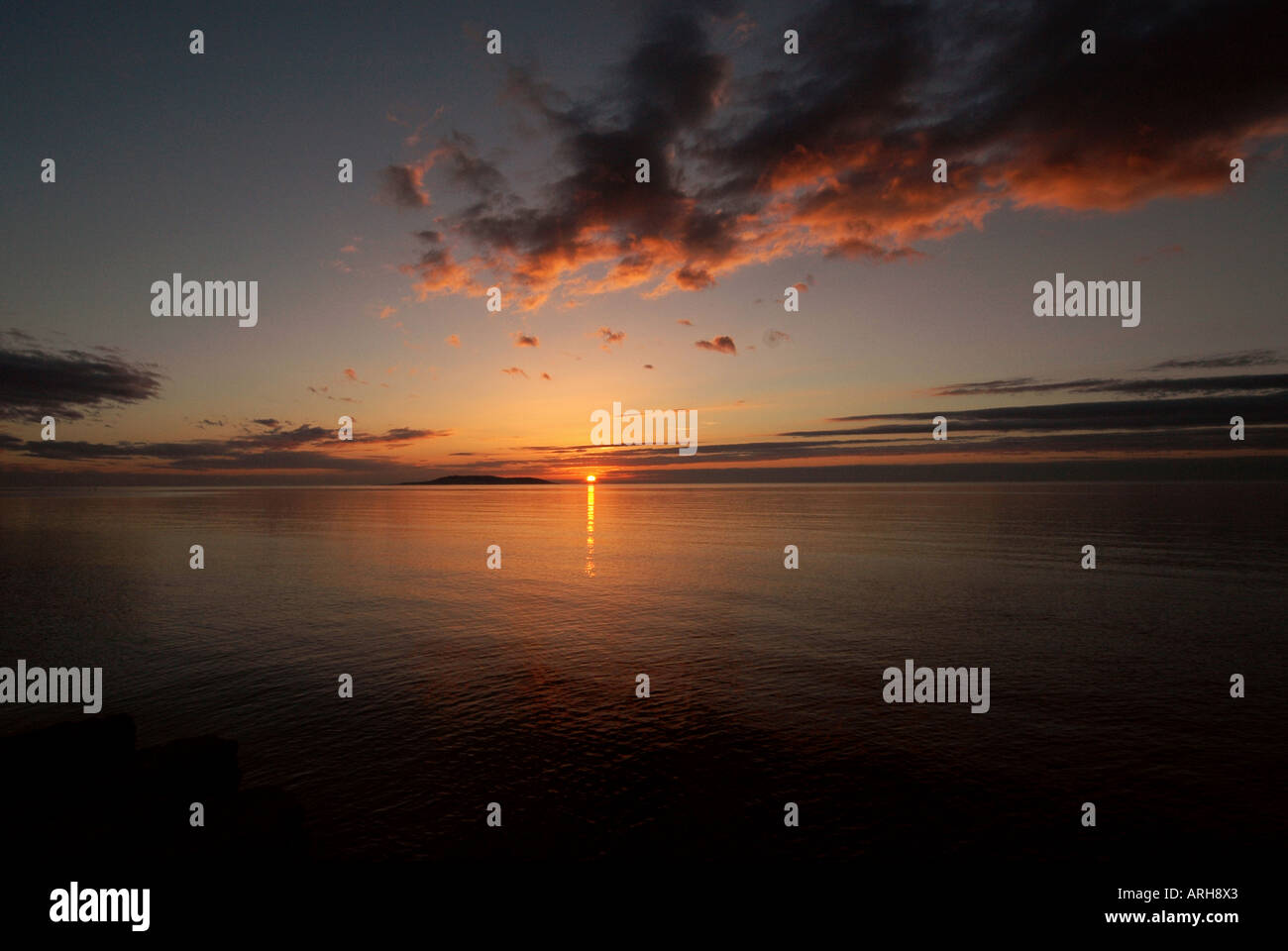 A general view of the sun setting over the town of Portmarnock pictured in Ireland. The sun is setting out to sea. Stock Photo