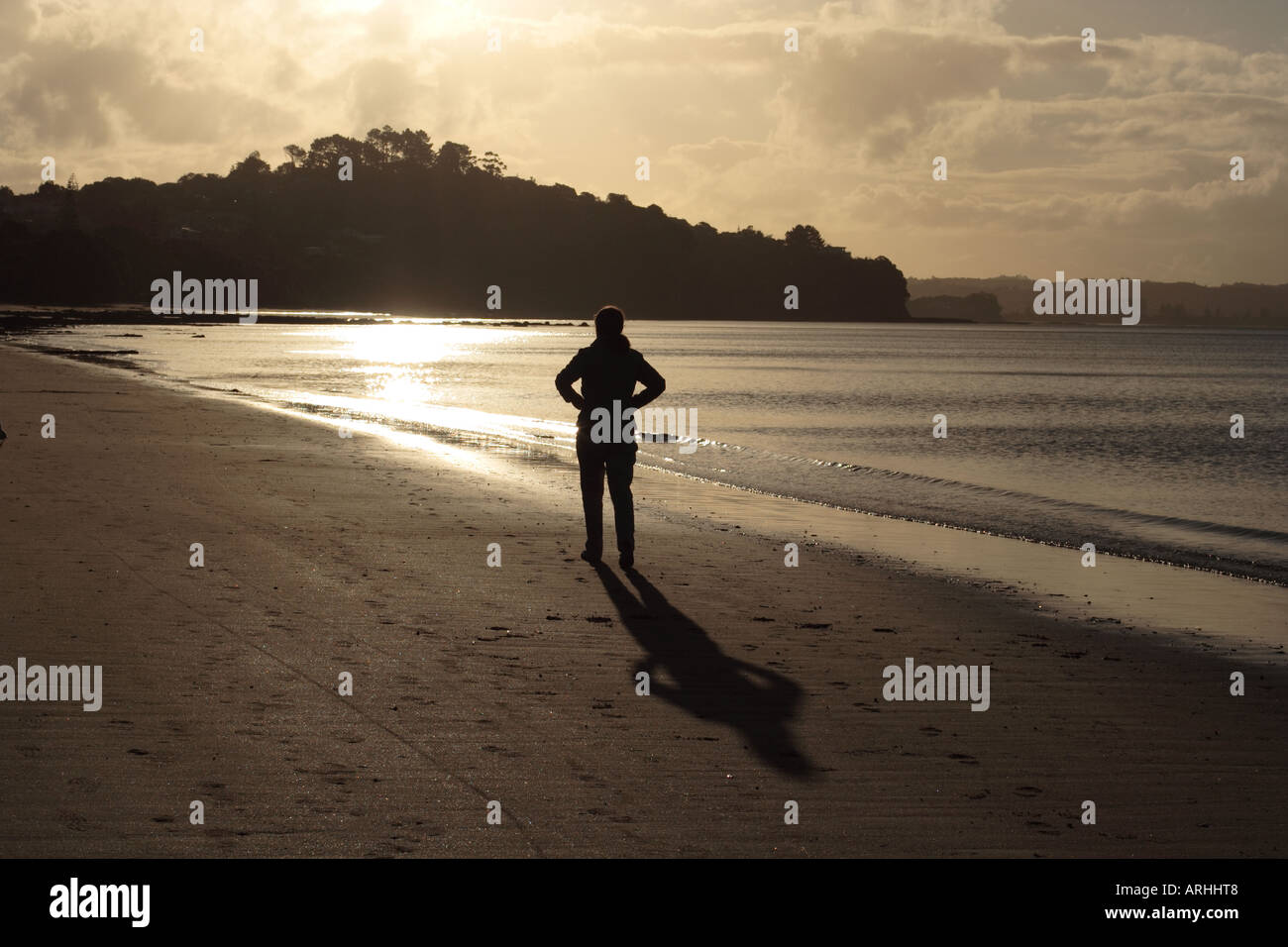 Silhouette of a woman on the beach looking at the sun. Stock Photo