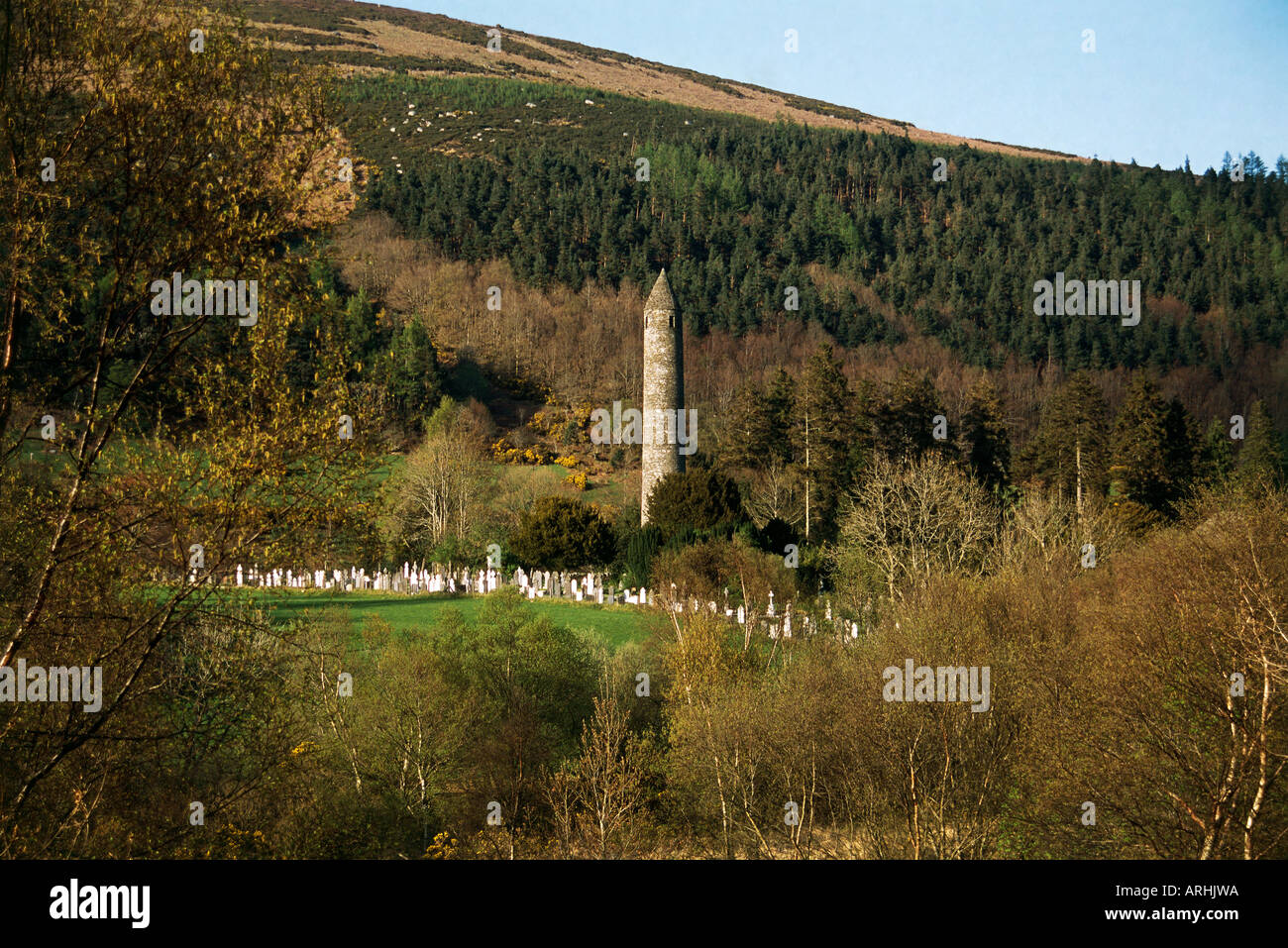A 12th century round tower amongst trees at Glendalough in the Wicklow Mountains National Park Stock Photo
